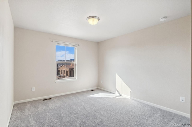 unfurnished room featuring carpet, visible vents, and baseboards