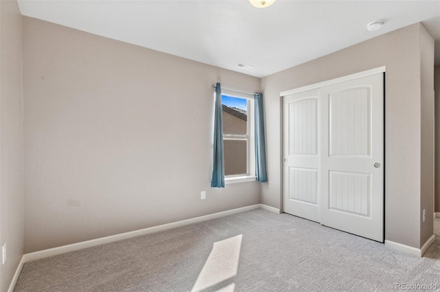 unfurnished bedroom with light carpet, visible vents, a closet, and baseboards