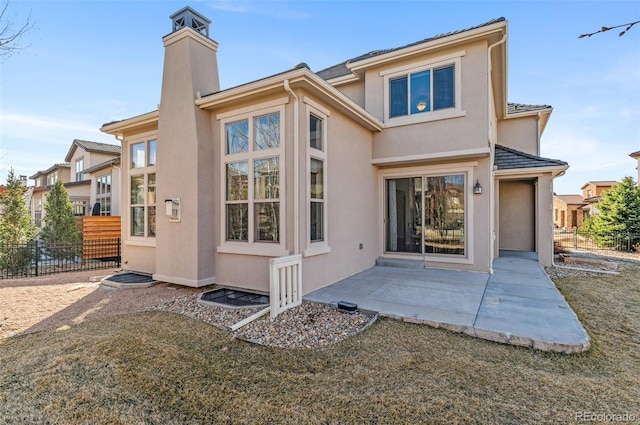 back of property featuring stucco siding, a chimney, a patio, and fence