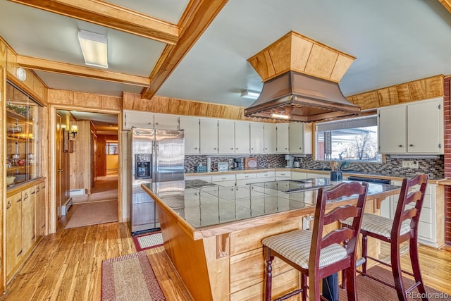 kitchen featuring a kitchen breakfast bar, stainless steel fridge, stovetop, and light hardwood / wood-style floors