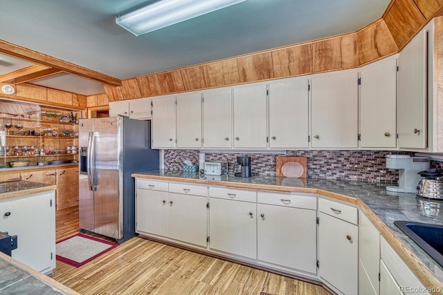 kitchen with sink, stainless steel refrigerator with ice dispenser, tasteful backsplash, light hardwood / wood-style floors, and white cabinetry