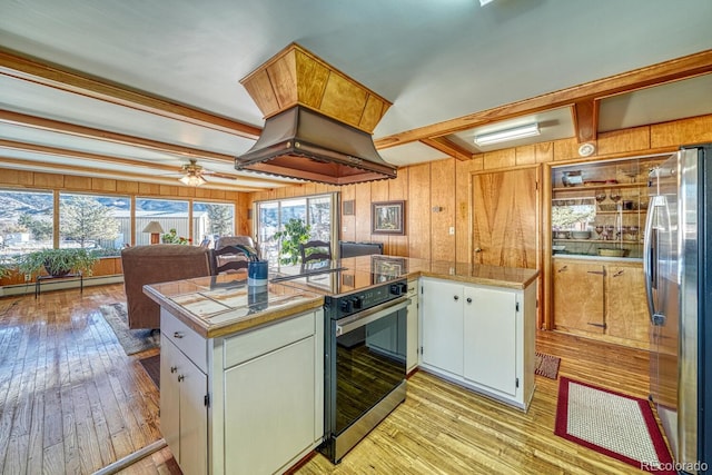 kitchen with stainless steel appliances, a baseboard heating unit, kitchen peninsula, wooden walls, and white cabinets