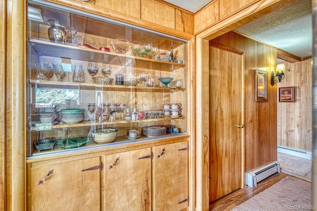 bar with wood walls, hardwood / wood-style floors, and a baseboard heating unit