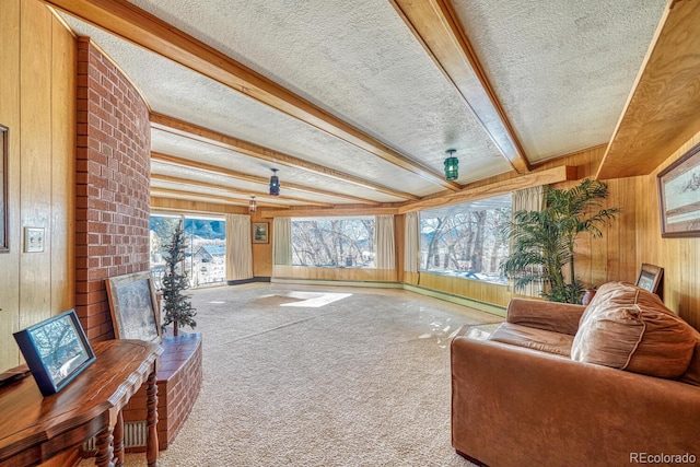 living room with beam ceiling, wooden walls, carpet, and a textured ceiling