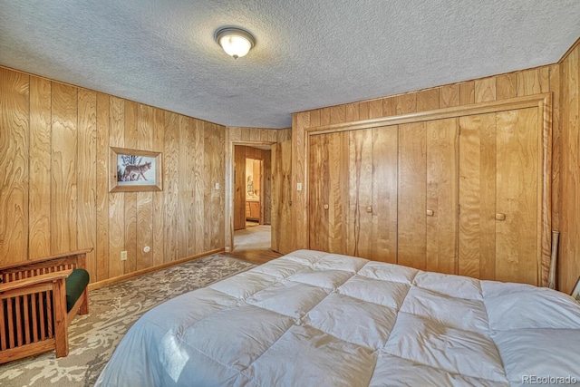 carpeted bedroom with wood walls, a textured ceiling, and a closet