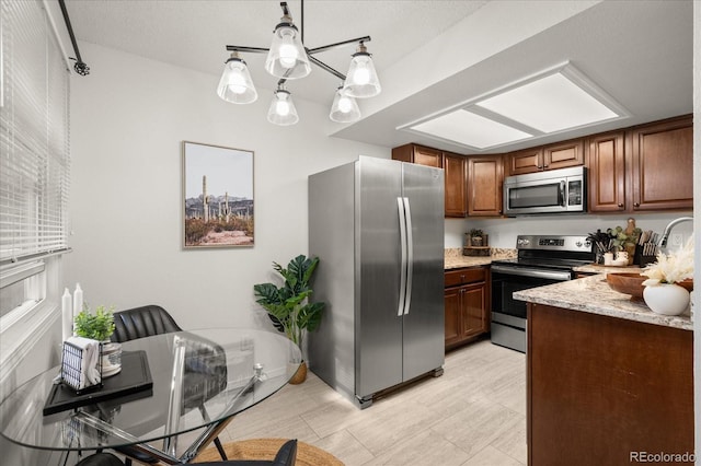 670 Winona Ct Unit 38, Denver, CO 80204 - kitchen with stainless steel appliances, light stone countertops, brown cabinets, a sink, and pendant lighting