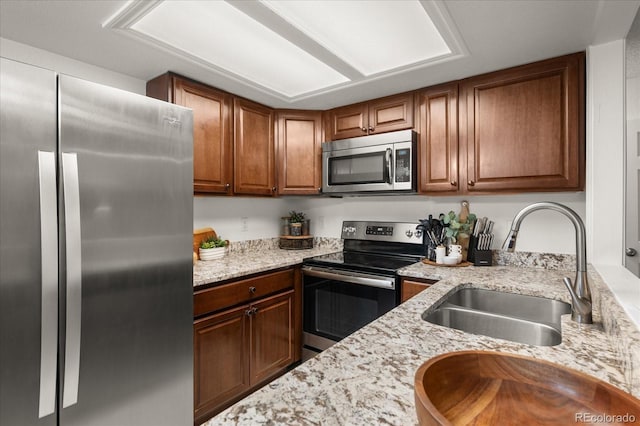 670 Winona Ct Unit 38, Denver, CO 80204 - kitchen featuring stainless steel appliances, a sink, light stone countertops, and brown cabinetry