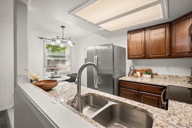 670 Winona Ct Unit 38, Denver, CO 80204 - kitchen with freestanding refrigerator, a sink, light stone counters, decorative light fixtures, and a textured ceiling