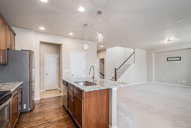 17187 E Cedar Gulch Dr, Parker, CO 80134 - kitchen featuring an island with sink, light stone counters, appliances with stainless steel finishes, decorative light fixtures, and brown cabinetry