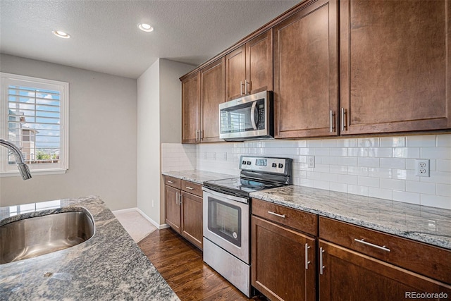 17187 E Cedar Gulch Dr, Parker, CO 80134 - kitchen with appliances with stainless steel finishes, light stone counters, decorative backsplash, a textured ceiling, and dark wood finished floors