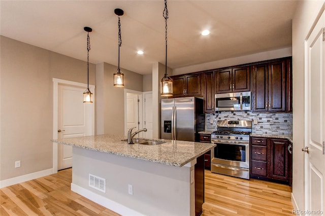 767 Robert St, Longmont, CO 80503 - kitchen with stainless steel appliances, a sink, light wood-style floors, tasteful backsplash, and dark brown cabinetry