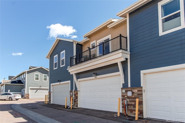 767 Robert St, Longmont, CO 80503 - view of side of property featuring a balcony, stone siding, and a garage