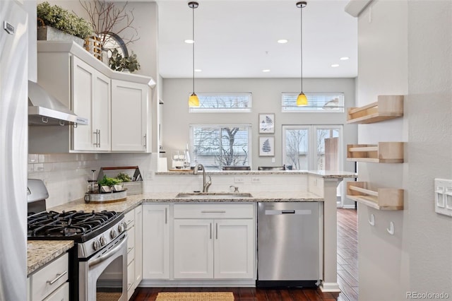 kitchen with white cabinets, kitchen peninsula, appliances with stainless steel finishes, and pendant lighting