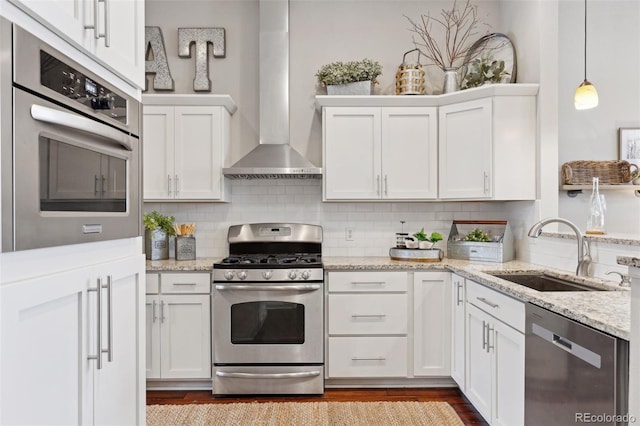 kitchen featuring sink, stainless steel appliances, white cabinetry, and wall chimney range hood