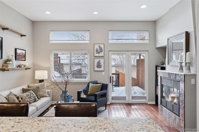 living room featuring wood-type flooring, a tiled fireplace, and a healthy amount of sunlight