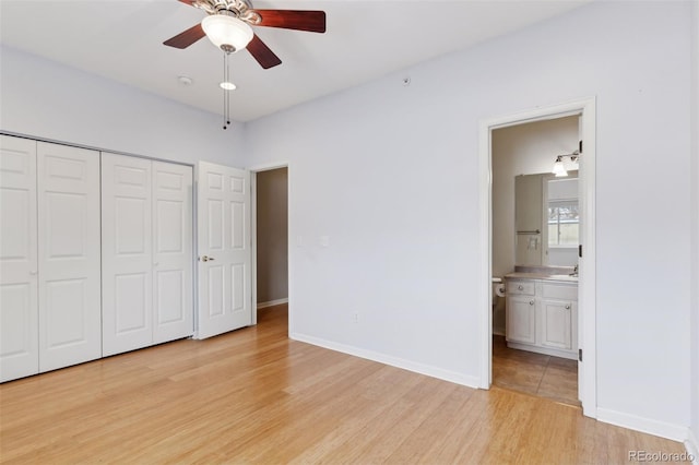 unfurnished bedroom featuring light wood-type flooring, ensuite bathroom, a closet, and ceiling fan