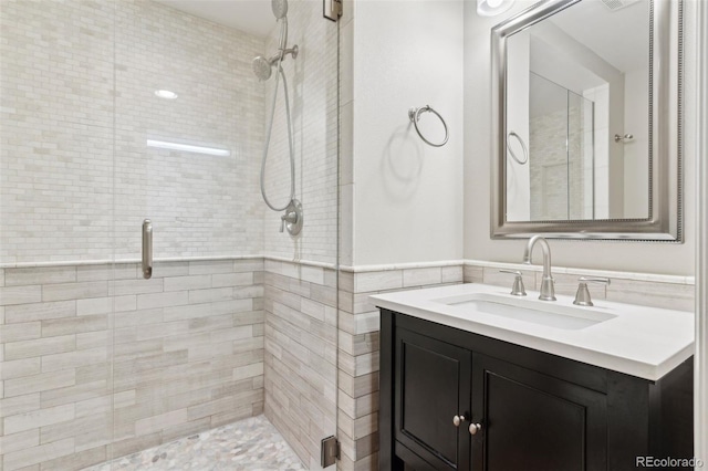 bathroom with tile walls, a shower with shower door, and vanity