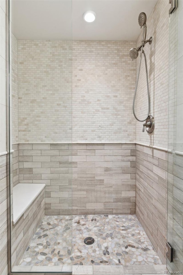 bathroom with a shower with shower door and tile walls