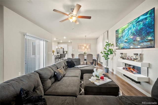 living room with hardwood / wood-style floors and ceiling fan with notable chandelier