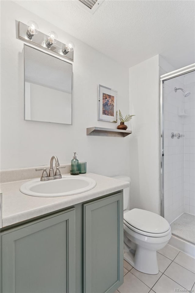 full bathroom featuring a textured ceiling, a stall shower, vanity, tile patterned floors, and toilet
