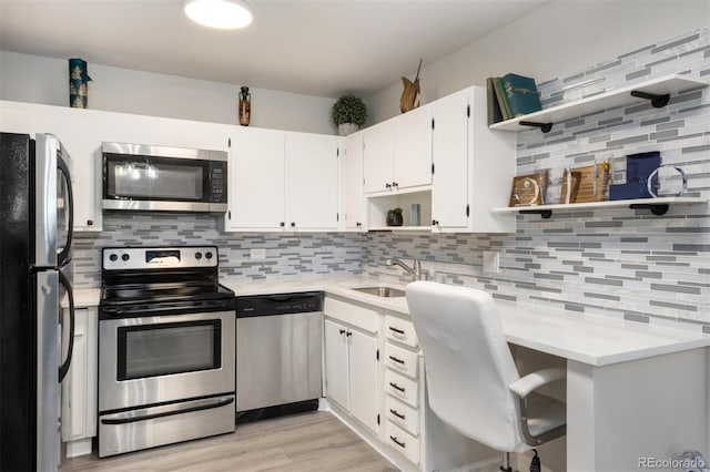 kitchen featuring tasteful backsplash, stainless steel appliances, light countertops, open shelves, and a sink