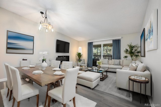 dining space with a textured ceiling, wood finished floors, an inviting chandelier, and vaulted ceiling