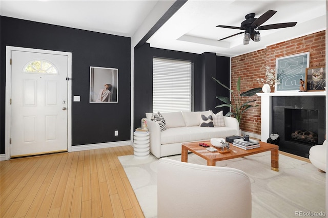 living room with light hardwood / wood-style flooring, ceiling fan, and brick wall