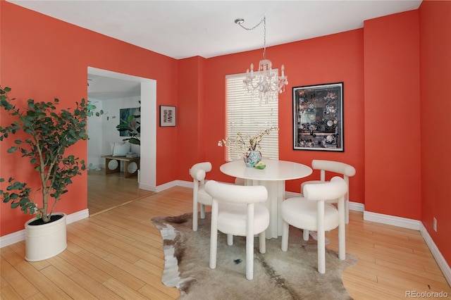 dining space with wood-type flooring and an inviting chandelier