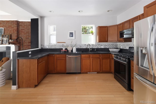 kitchen featuring stainless steel appliances, light wood-type flooring, tasteful backsplash, and sink