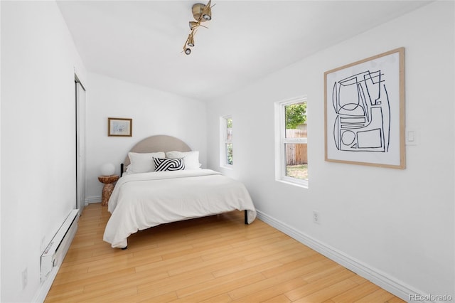 bedroom with baseboard heating and light hardwood / wood-style floors