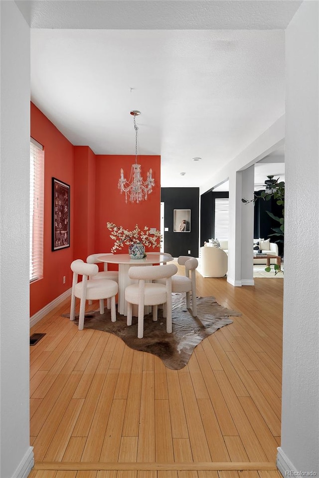 dining space with wood-type flooring and an inviting chandelier