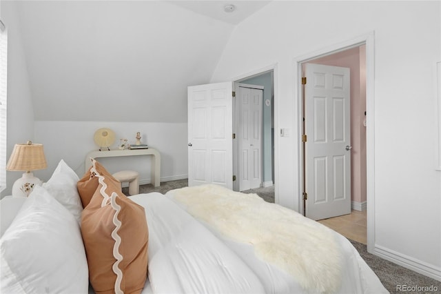 bedroom with light colored carpet and lofted ceiling