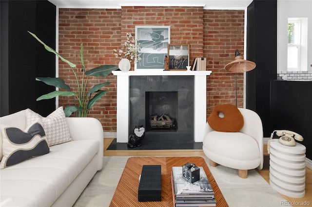 living room with brick wall, light hardwood / wood-style flooring, and a tile fireplace