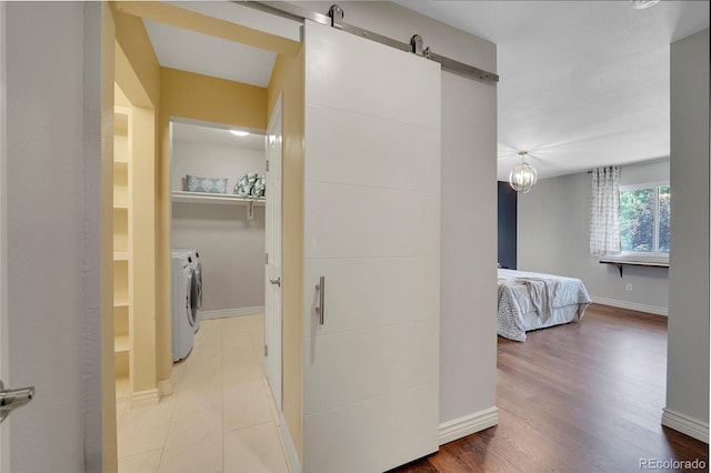 hall with a barn door, hardwood / wood-style floors, and washer and dryer