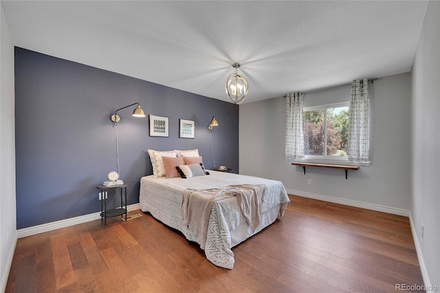 bedroom with hardwood / wood-style floors and a notable chandelier