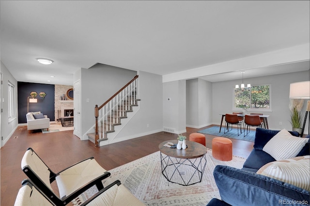 living room featuring a chandelier, a large fireplace, and dark wood-type flooring