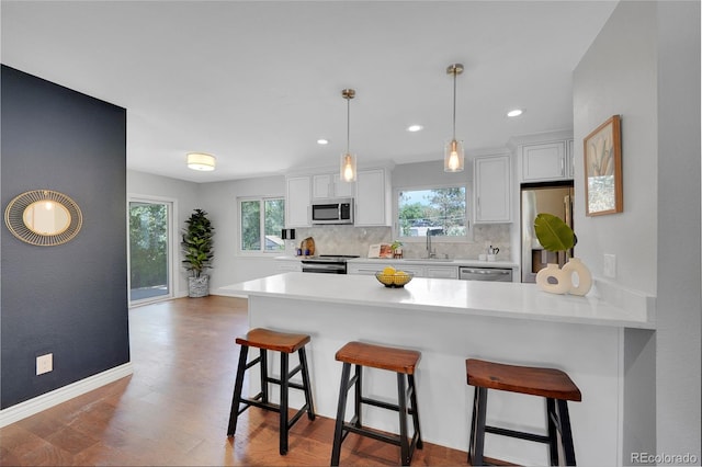 kitchen with a healthy amount of sunlight, hanging light fixtures, white cabinets, and stainless steel appliances