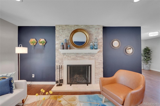 living room with wood-type flooring and a stone fireplace