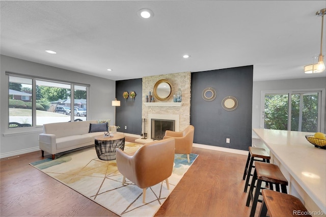 living room featuring light wood-type flooring, a brick fireplace, and a healthy amount of sunlight