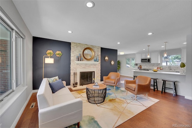 living room with a large fireplace, sink, and light hardwood / wood-style flooring