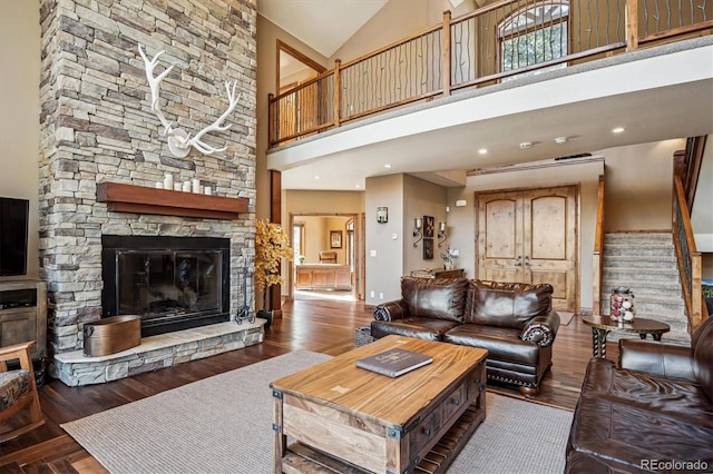 living area featuring stairs, high vaulted ceiling, dark wood-style flooring, and a fireplace