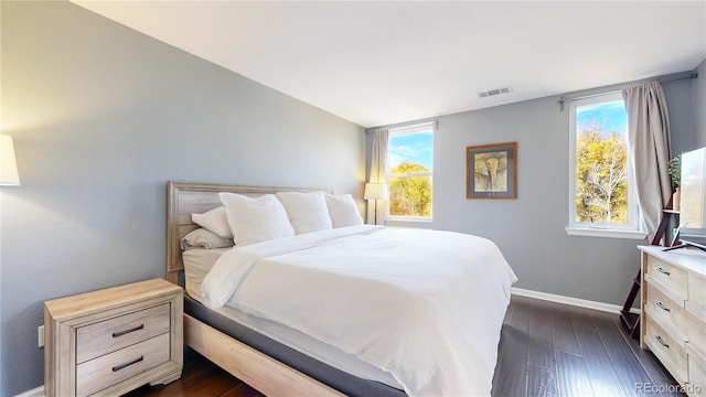 bedroom with multiple windows and dark hardwood / wood-style flooring