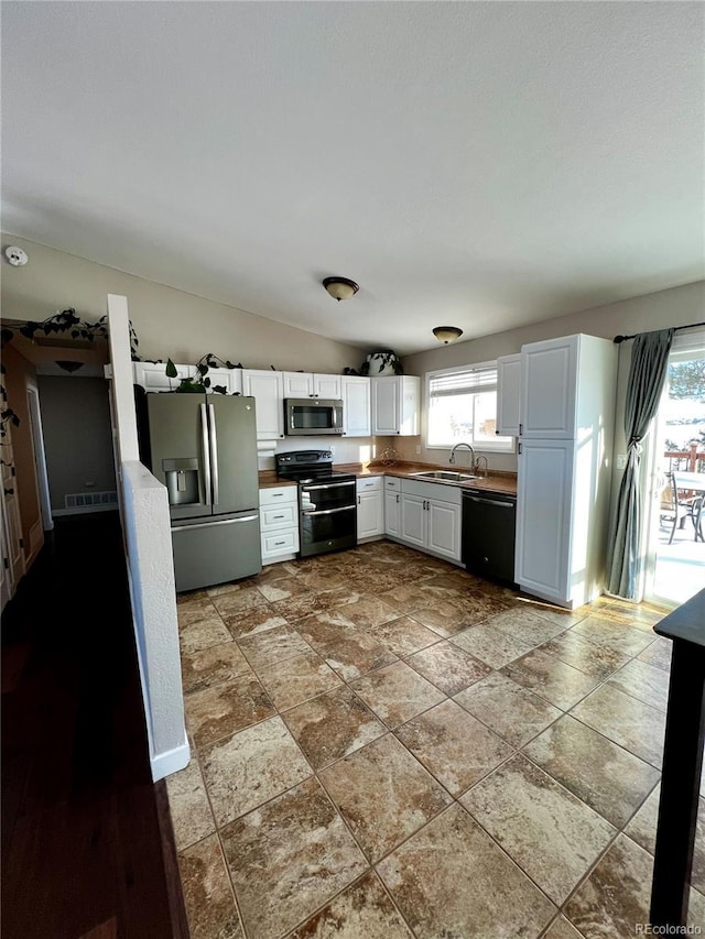 kitchen featuring sink, white cabinetry, a wealth of natural light, and appliances with stainless steel finishes