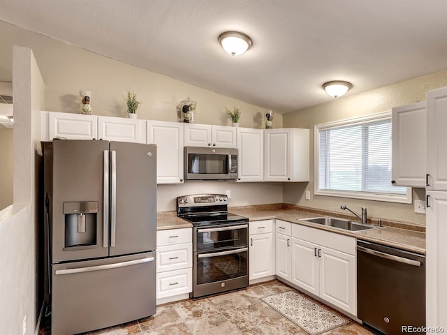 kitchen with sink, white cabinets, lofted ceiling, and stainless steel appliances