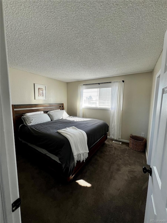 bedroom with dark carpet and a textured ceiling