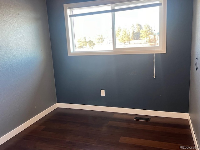 empty room featuring dark wood-type flooring and a wealth of natural light