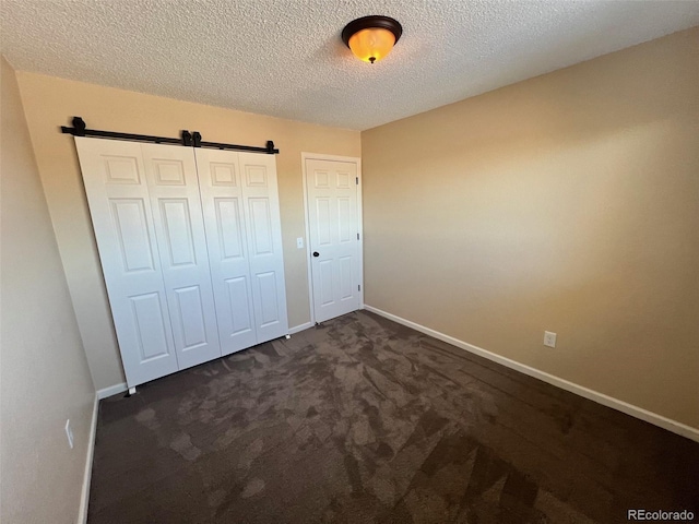 unfurnished bedroom with dark colored carpet and a textured ceiling