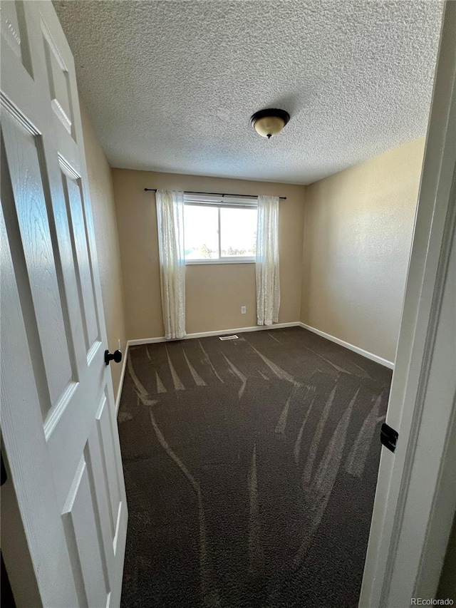 carpeted empty room with a textured ceiling