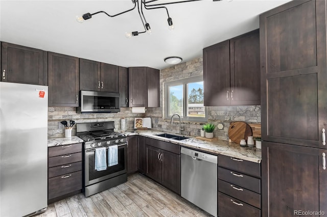 6254 W 79th Ave, Arvada, CO 80003 - kitchen featuring stainless steel appliances, dark brown cabinetry, backsplash, light stone counters, and light wood-style floors