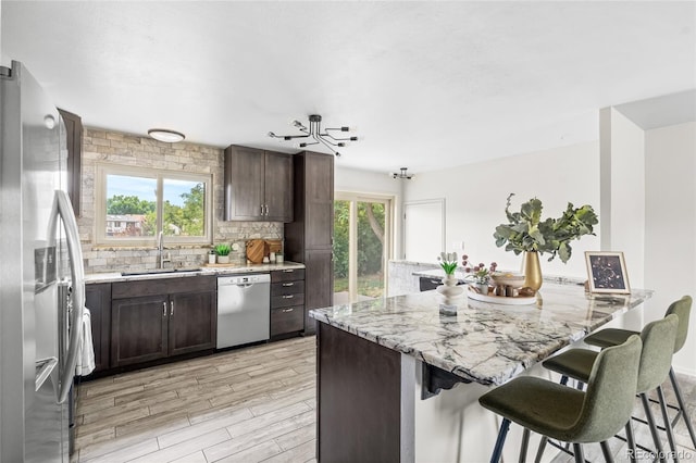 6254 W 79th Ave, Arvada, CO 80003 - kitchen featuring appliances with stainless steel finishes, a breakfast bar area, dark brown cabinetry, and light wood-type flooring